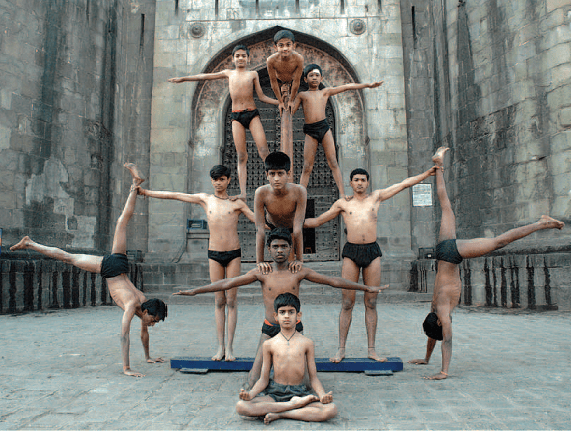 Athletes performing Mallakhamb on a wooden pole